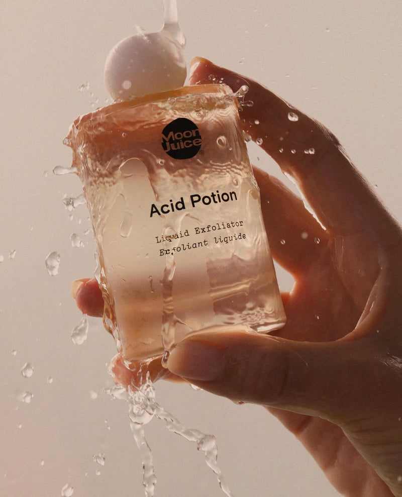 Hand holding a 'Moon Juice Acid Potion' product with water splashes.
